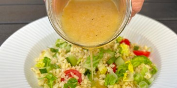 Dressing hældes over en bulgursalat.